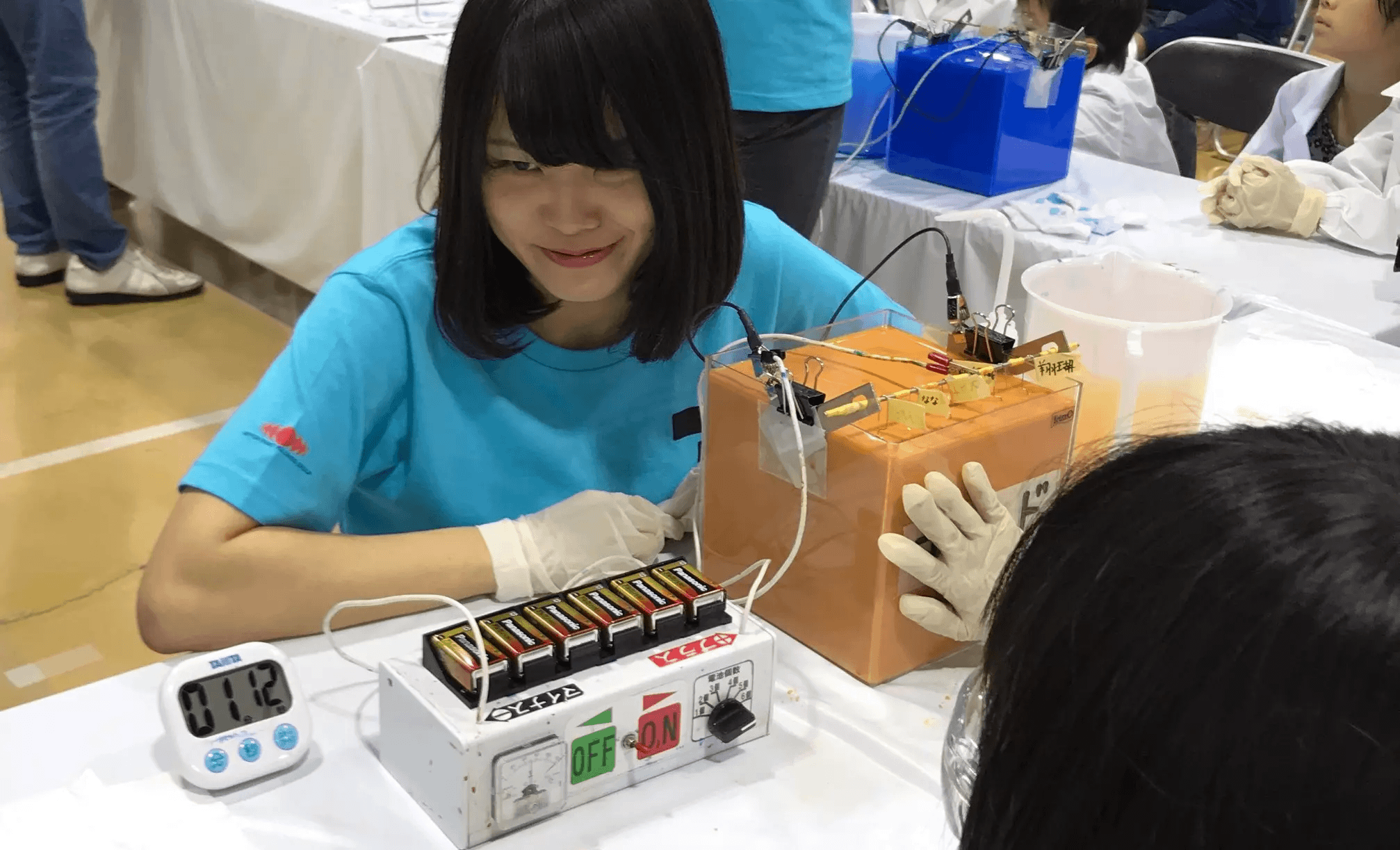 Employee volunteers explaining electrodeposition coating to children